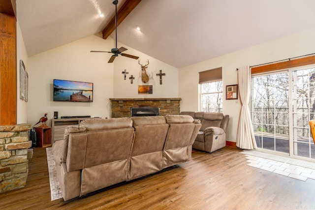 living area featuring beam ceiling, a stone fireplace, high vaulted ceiling, and wood finished floors