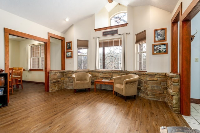 living area with baseboards, high vaulted ceiling, and wood finished floors