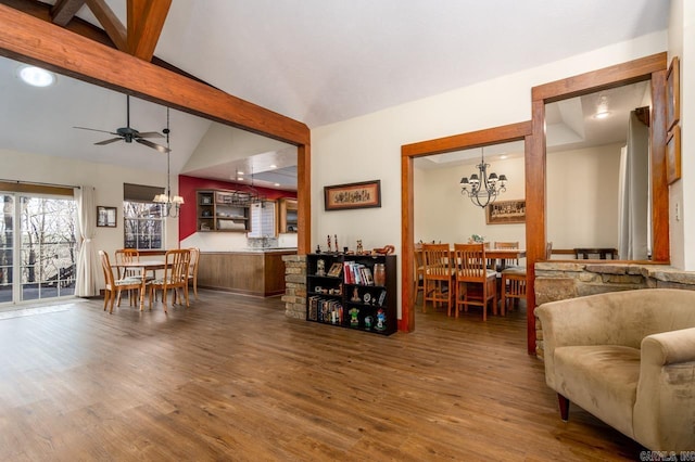 living room featuring ceiling fan with notable chandelier, vaulted ceiling with beams, and wood finished floors