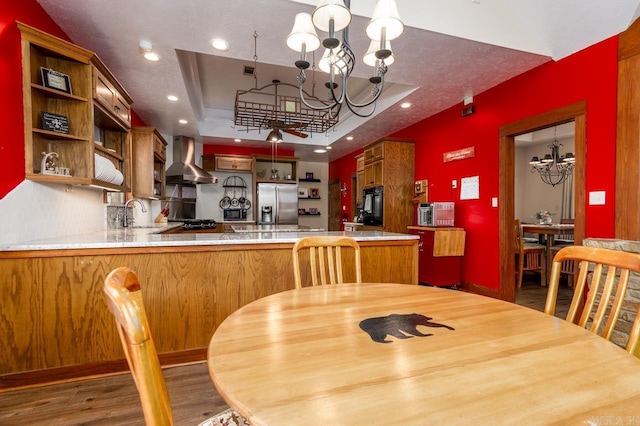 dining space with a notable chandelier, recessed lighting, a tray ceiling, and wood finished floors