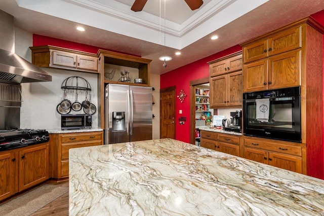 kitchen featuring wall chimney range hood, a tray ceiling, ornamental molding, black appliances, and open shelves