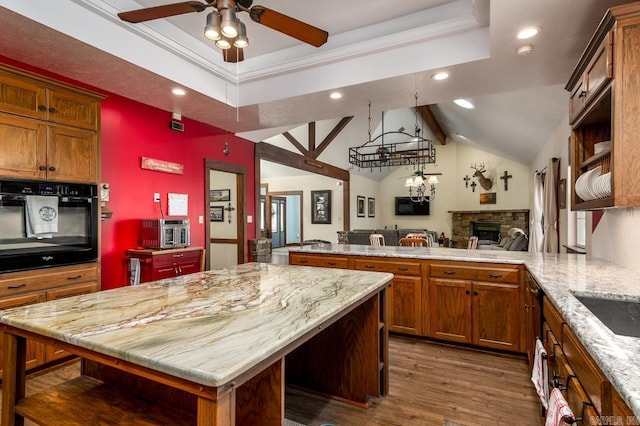 kitchen with oven, a peninsula, light stone countertops, dark wood-style flooring, and vaulted ceiling