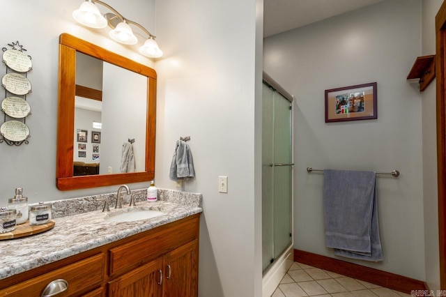 full bath featuring tile patterned floors, baseboards, vanity, and a shower stall