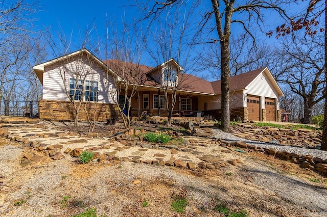 single story home with an attached garage, covered porch, and stone siding