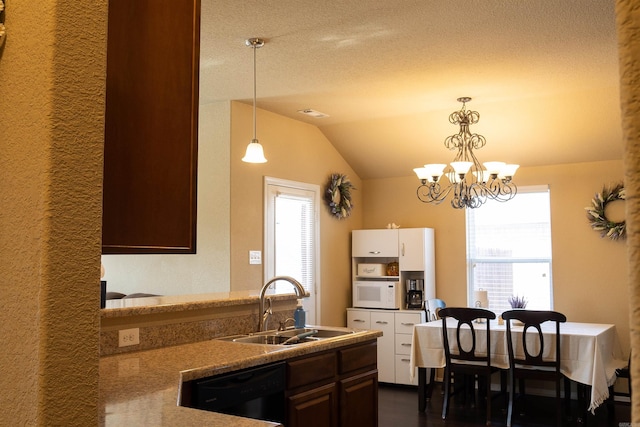 kitchen featuring a sink, white microwave, dishwasher, vaulted ceiling, and hanging light fixtures