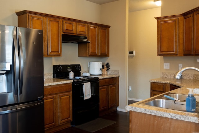 kitchen featuring black electric range, under cabinet range hood, a sink, dark wood-style floors, and stainless steel fridge