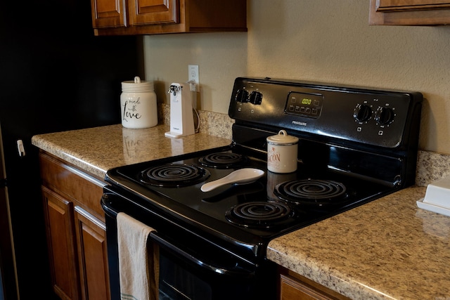 kitchen featuring brown cabinetry, light countertops, and black / electric stove