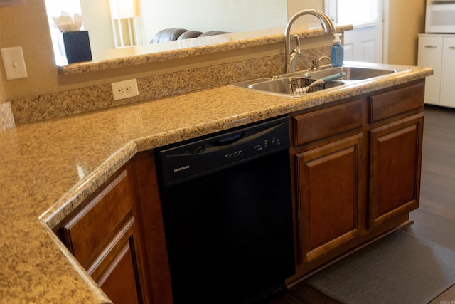 kitchen with white microwave, a sink, light countertops, black dishwasher, and brown cabinets