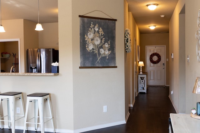 hall featuring a sink, baseboards, and dark wood-type flooring