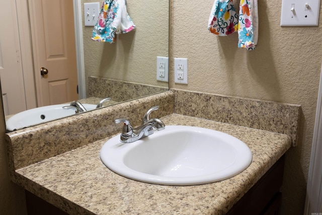 bathroom with vanity and a textured wall