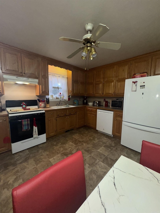 kitchen with under cabinet range hood, light countertops, white appliances, a ceiling fan, and a sink