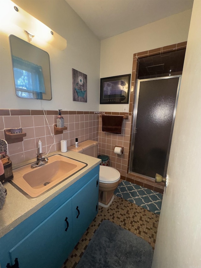 full bathroom featuring toilet, tile walls, wainscoting, a shower stall, and vanity