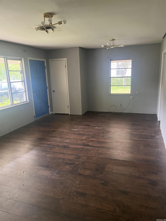 unfurnished room with dark wood-style flooring and a notable chandelier