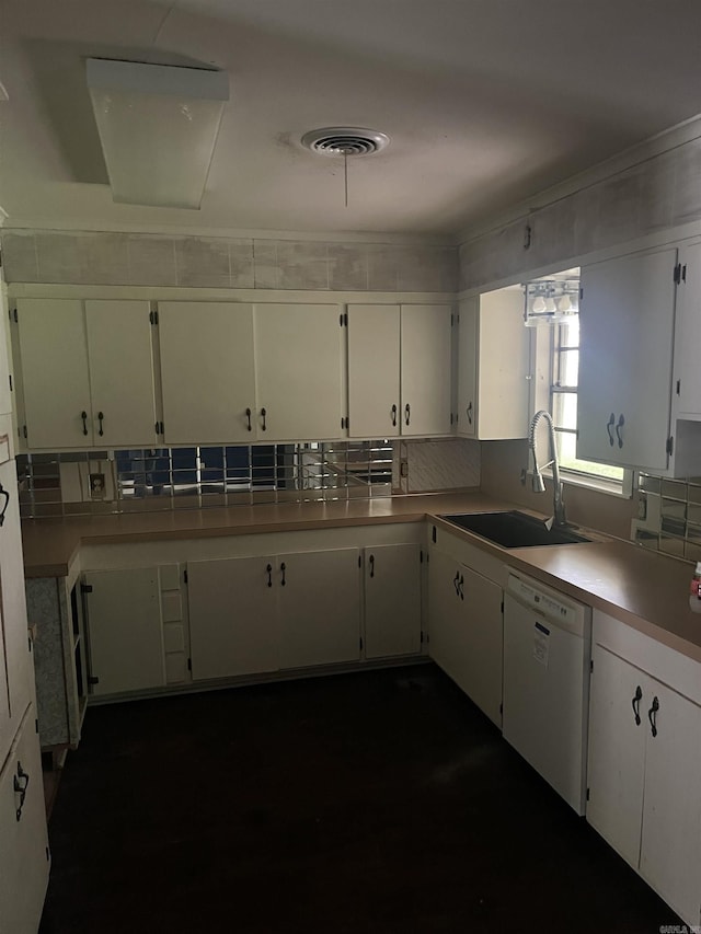 kitchen with white dishwasher, a sink, light countertops, white cabinetry, and visible vents