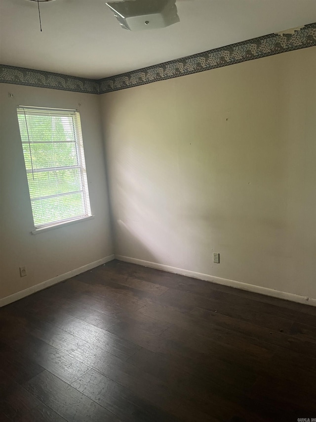 spare room with dark wood-type flooring and baseboards