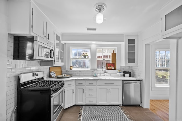 kitchen with visible vents, a sink, backsplash, appliances with stainless steel finishes, and white cabinets