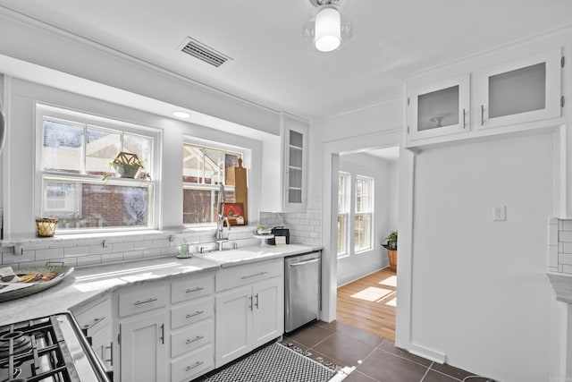 kitchen featuring tasteful backsplash, visible vents, dishwasher, white cabinets, and a sink