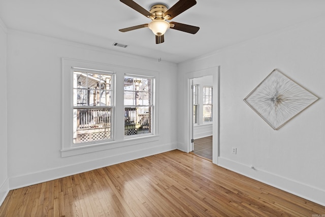 empty room featuring ceiling fan, visible vents, baseboards, and hardwood / wood-style floors