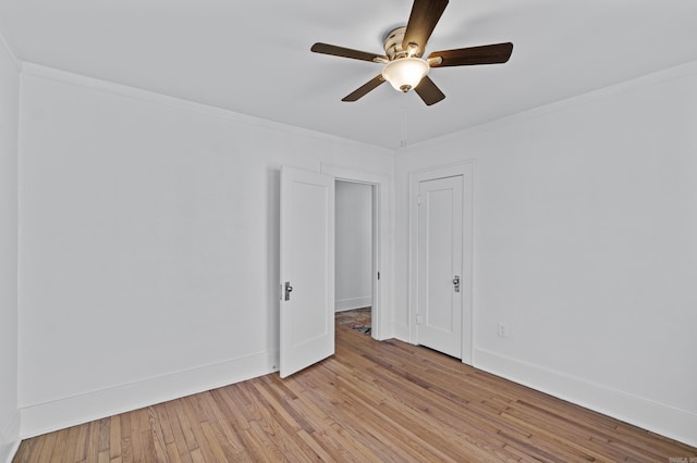 spare room featuring light wood-style flooring, ceiling fan, baseboards, and ornamental molding