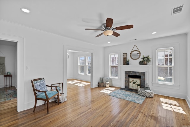 living area with a tiled fireplace, recessed lighting, visible vents, and hardwood / wood-style floors