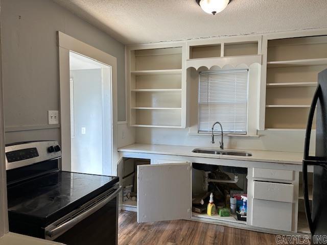 kitchen featuring open shelves, a sink, a textured ceiling, freestanding refrigerator, and stainless steel range with electric cooktop