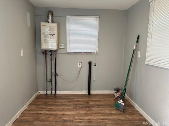 laundry area with baseboards, hookup for an electric dryer, wood finished floors, and water heater