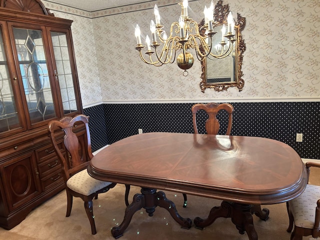 dining area featuring wallpapered walls, a wainscoted wall, a chandelier, and light carpet