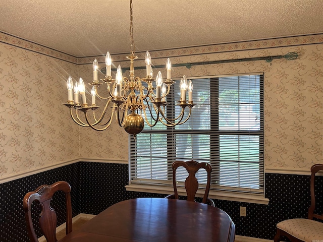 dining space with wainscoting, a textured ceiling, and wallpapered walls