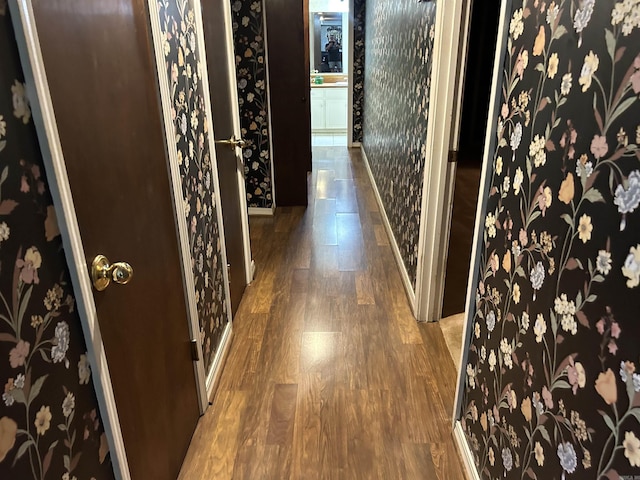 hall with baseboards, wood finished floors, and wallpapered walls