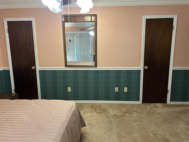 bedroom featuring carpet flooring, wallpapered walls, a wainscoted wall, and ornamental molding