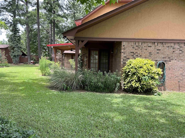 view of side of home featuring a yard and brick siding