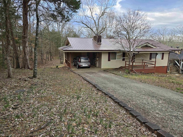 view of front of home with metal roof, a carport, a chimney, and aphalt driveway