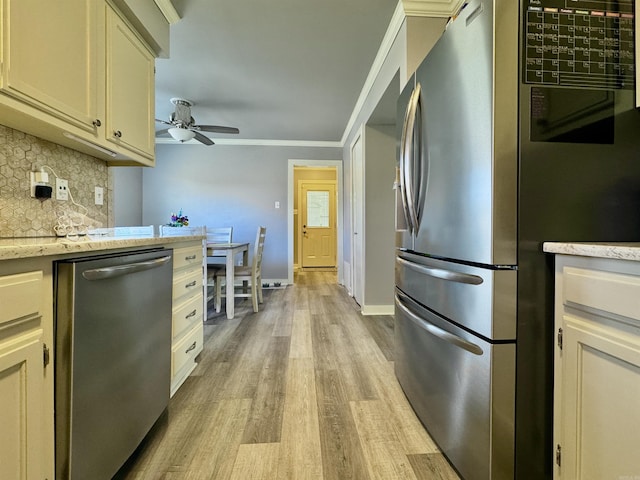 kitchen with baseboards, light wood-style flooring, ceiling fan, appliances with stainless steel finishes, and tasteful backsplash