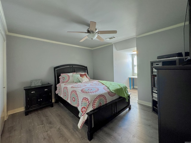 bedroom with visible vents, ornamental molding, baseboards, and wood finished floors