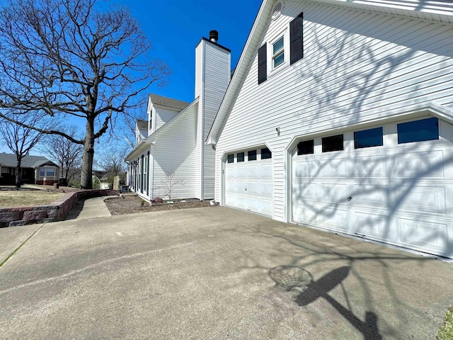 view of property exterior featuring aphalt driveway, a garage, and a chimney