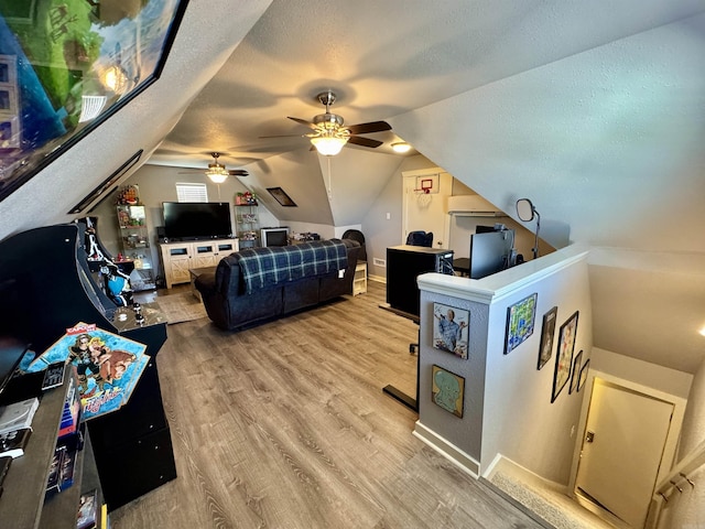 living area featuring ceiling fan, lofted ceiling, wood finished floors, and a textured ceiling