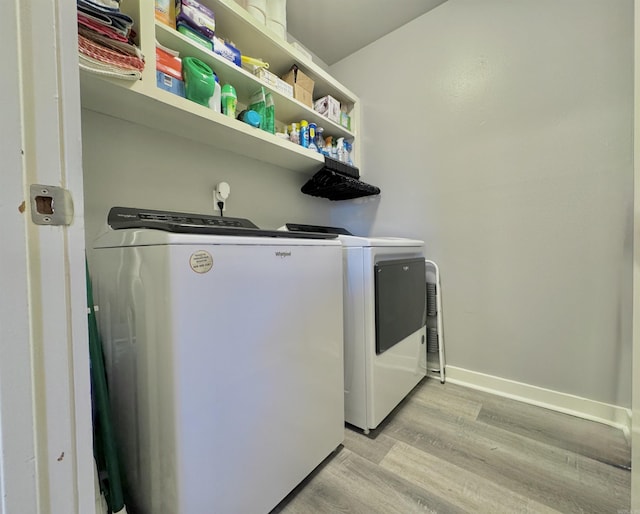 clothes washing area featuring laundry area, baseboards, independent washer and dryer, and light wood-type flooring