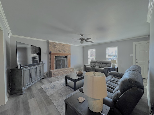 living area featuring a brick fireplace, light wood finished floors, and ornamental molding