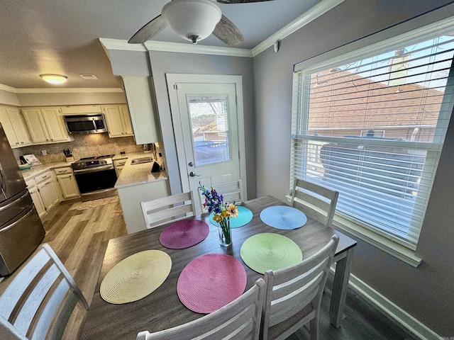 dining area featuring baseboards, a ceiling fan, light wood-type flooring, and ornamental molding