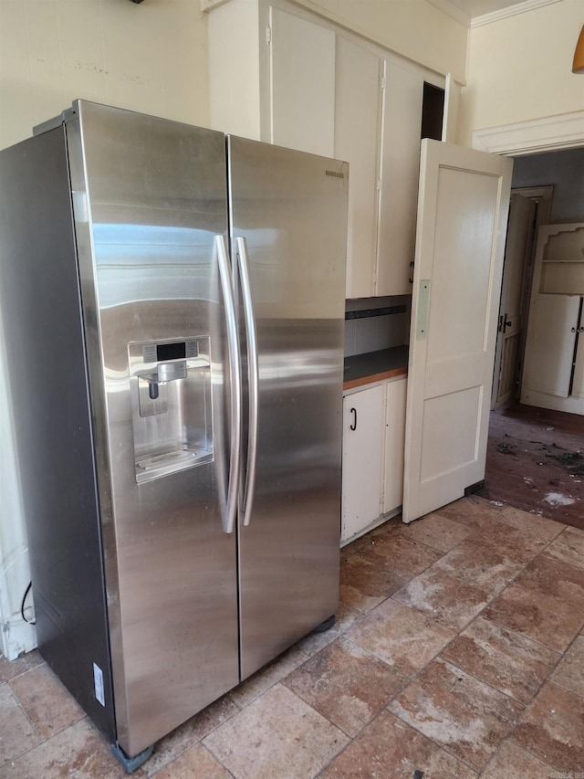 kitchen featuring dark countertops, stone finish floor, and stainless steel refrigerator with ice dispenser