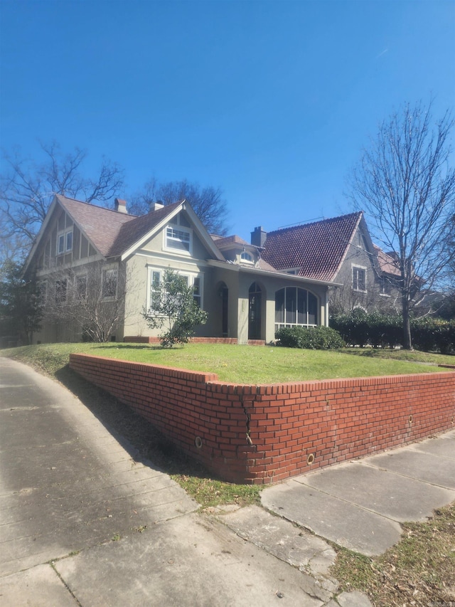 view of front facade with stucco siding, a chimney, and a front lawn