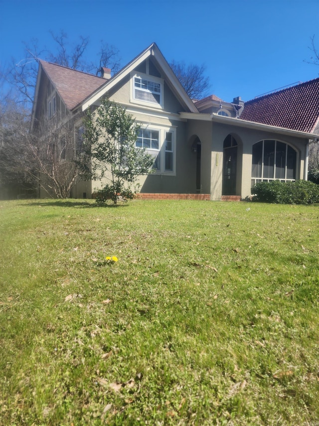 view of front of property with stucco siding, a chimney, and a front yard