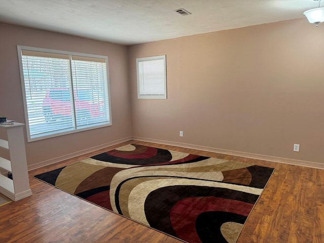 bedroom with wood finished floors, visible vents, and baseboards