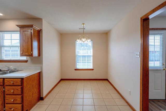 unfurnished dining area with a notable chandelier, visible vents, baseboards, and a sink