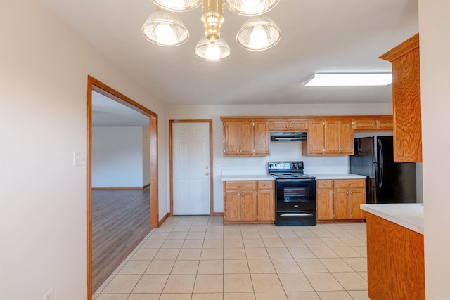 kitchen with black appliances, light tile patterned flooring, light countertops, and under cabinet range hood