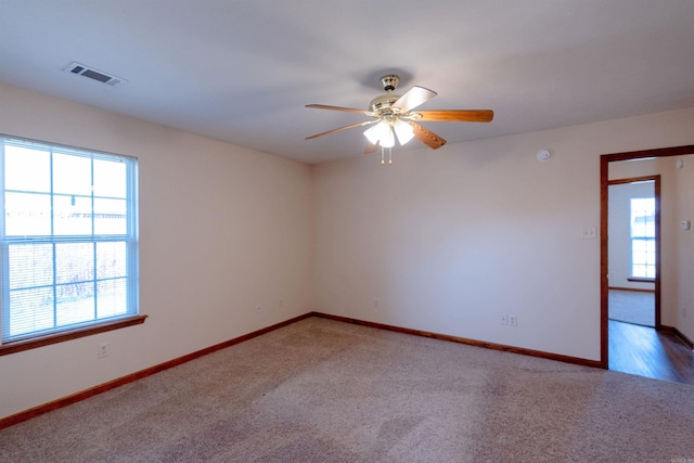 carpeted empty room featuring a ceiling fan, baseboards, and visible vents