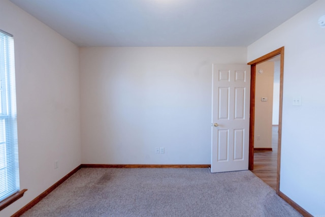 carpeted empty room featuring baseboards