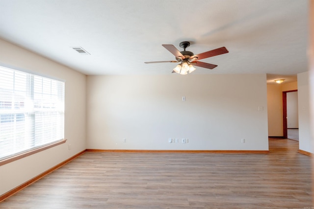 unfurnished room featuring a ceiling fan, light wood-style floors, visible vents, and baseboards