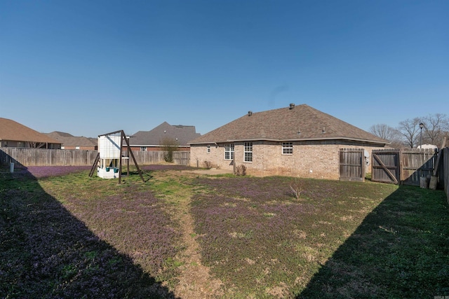 view of yard with a fenced backyard and a gate