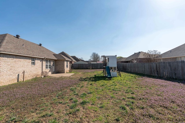 view of yard with a fenced backyard, a playground, and a patio